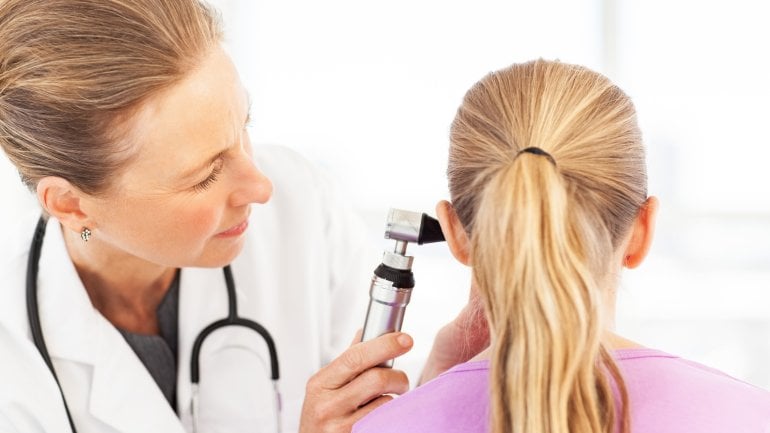 Eine Ärztin schaut mit einem Otoskop ins Ohr eines Mädchens.