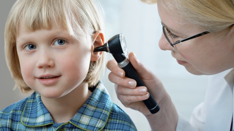 Das Bild zeigt eine Ärztin, die das Ohr eines Kindes untersucht.