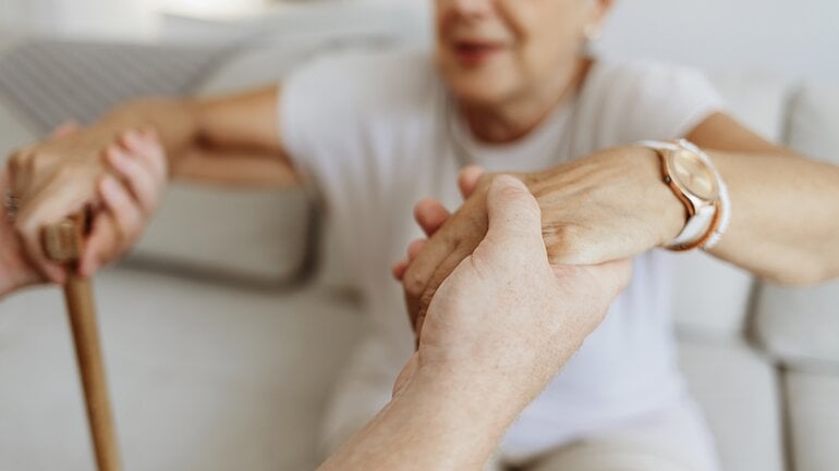 Mann hilft seiner Mutter beim Aufstehen