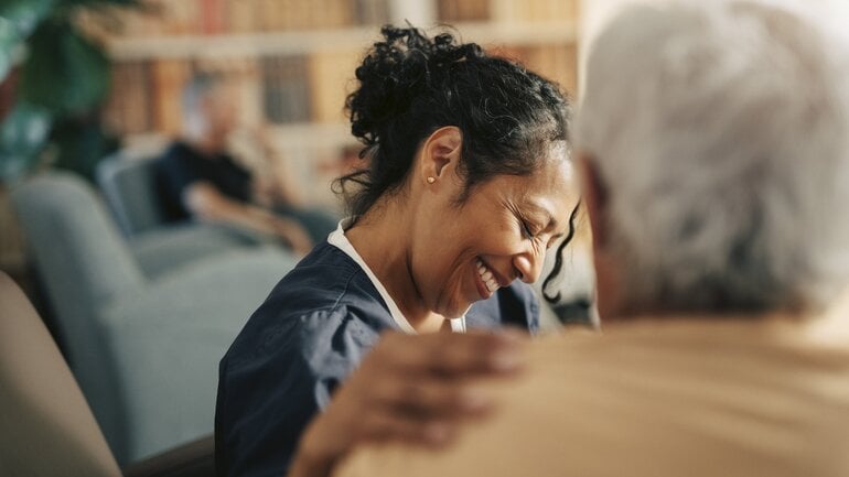 Pflegerin lacht mit Seniorin