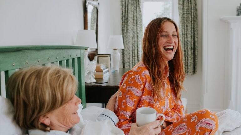 Lachende Frau pflegt ihre bettlägerige Mutter