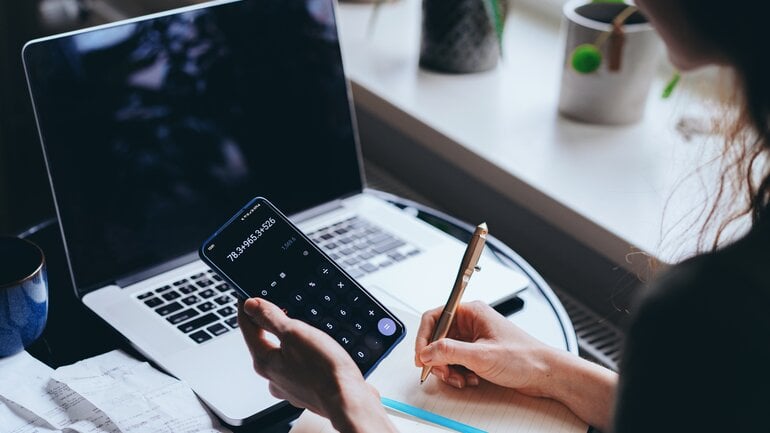 Frau berechnet etwas mit Taschenrechner