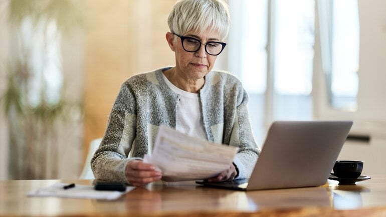 Frau mit Unterlagen am Laptop