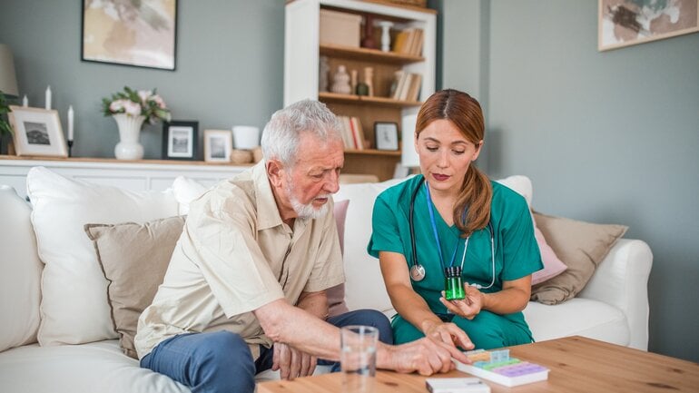 Pflegerin und älterer Mann beim Medikamentenmanagement