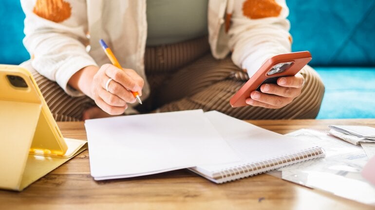Frau macht Papierkram mit Tablet und Handy