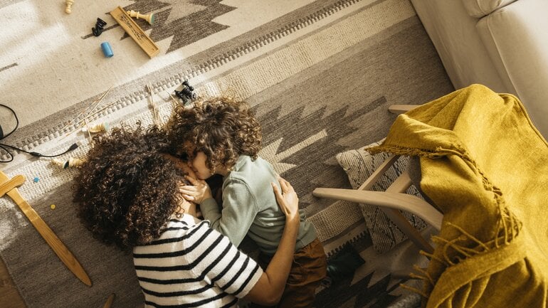 Mama und Kind kuscheln und toben auf dem Boden