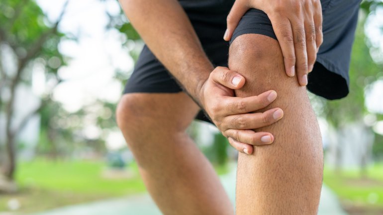 Mann mit Plica-Syndrom fasst sich ans schmerzende Knie.
