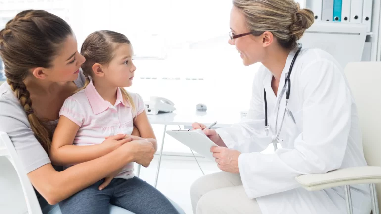 Ein kleines Mädchen auf dem Schoß der Mutter bei einer Ärztin.