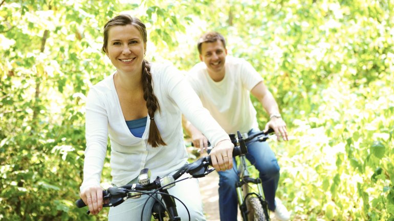 Das Bild zeigt ein Paar im Wald beim Radfahren.