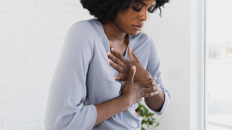 Refluxkrankheit: Frau hat Sodbrennen und hält sich die Brust