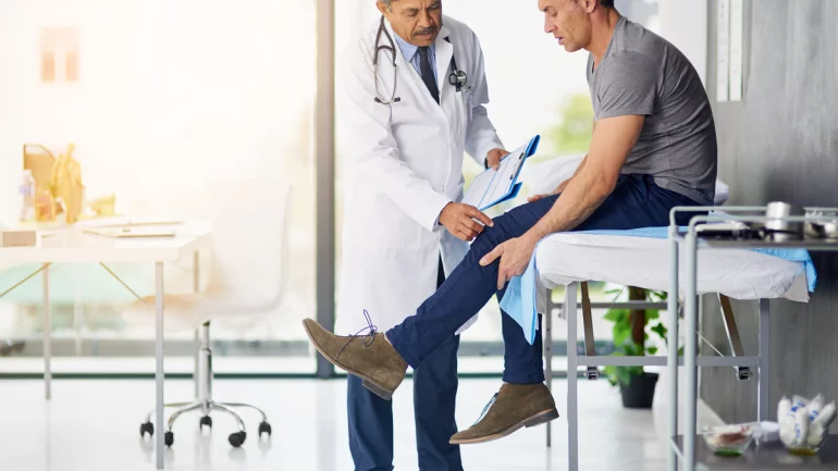 Ein Arzt betrachtet das Bein eines Patienten.