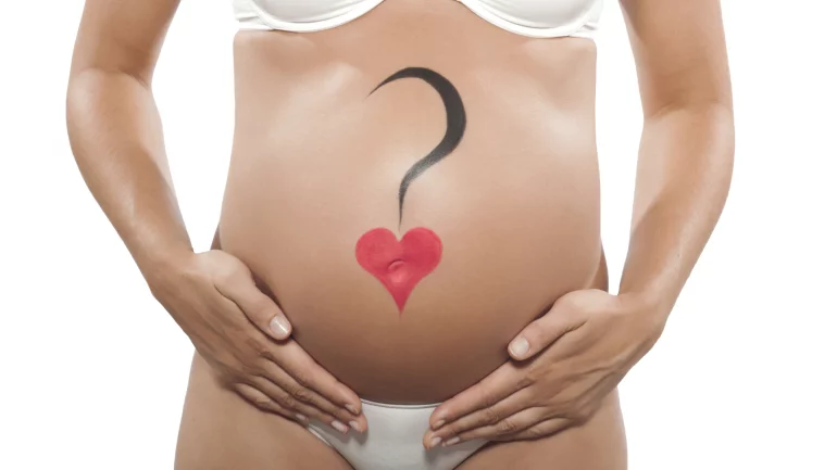 Schwangere mit Fragezeichen und Herz auf dem Bauch