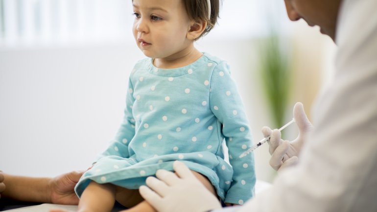 Ein Arzt verabreicht einem Kleinkind eine Injektion in den Oberschenkel.