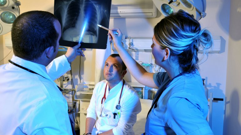 Drei Ärzte betrachten in der Notaufnahme ein Röntgenbild des Brustkorbs.