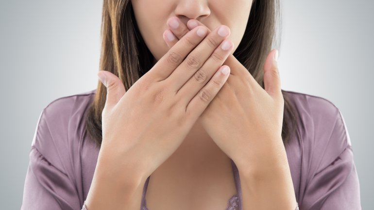 Eine Frau hält sich die Hände vor den Mund.