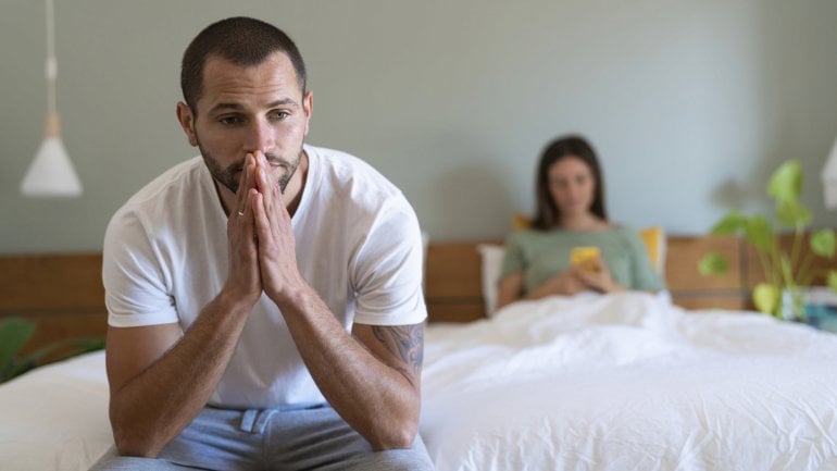 Schmerzen beim Sex: Mann sitzt nachdenklich im Bett