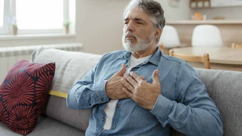 Brustschmerzen: Älterer Mann fasst sich an die Brust