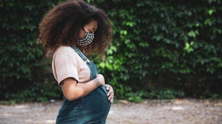 Eine schwangere Frau trägt einen Mundschutz