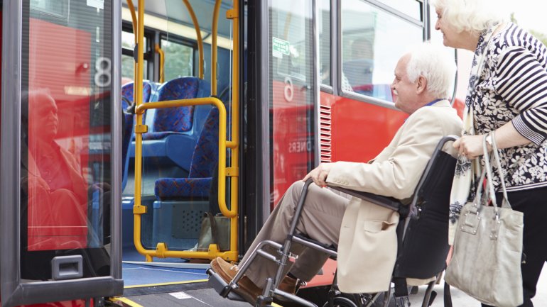 Das Bild zeigt einen Rollstuhlfahrer, der in einen Bus einsteigt. 