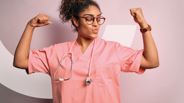 Eine junge Pflegekraft zeigt, dass sie stark ist und schaut auf ihre erhobenen Arme