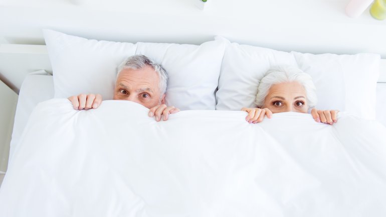 Ein älteres Paar liegt im Bett. 
