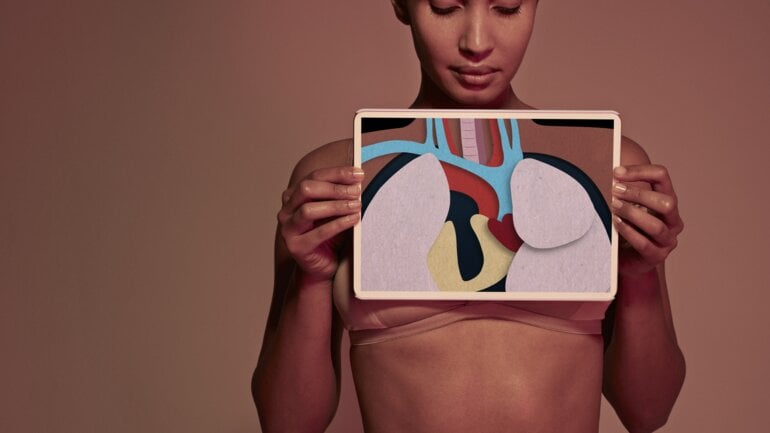 Situs inversus: Eine Frau hält ein Tablet vor ihren Körper in dem man Organe sieht