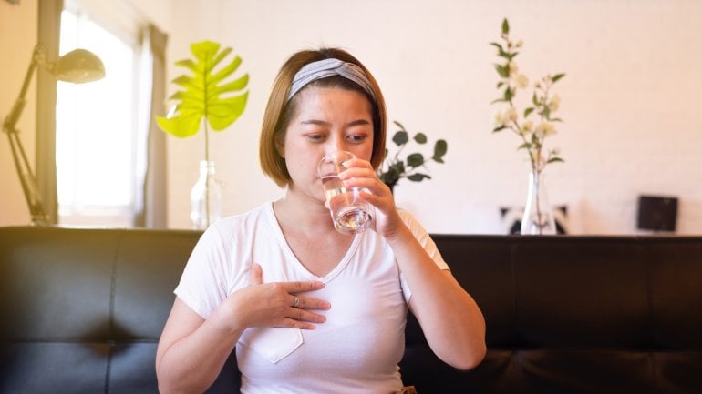 Frau trinkt ein Glas Wasser gegen Sodbrennen