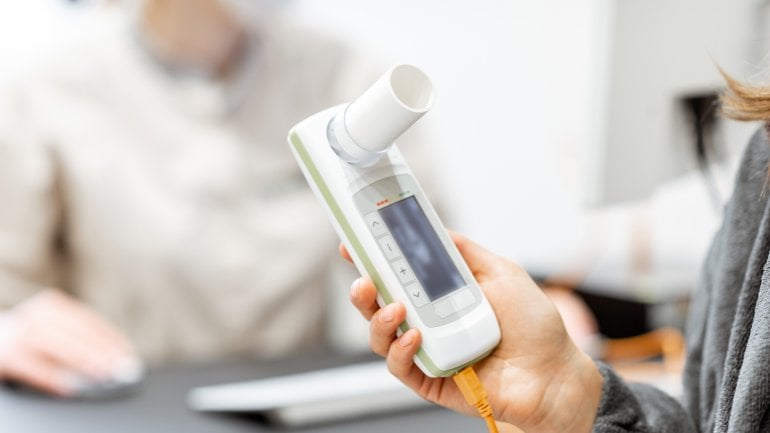 Frau hält Spirometrie-Gerät in der Hand.