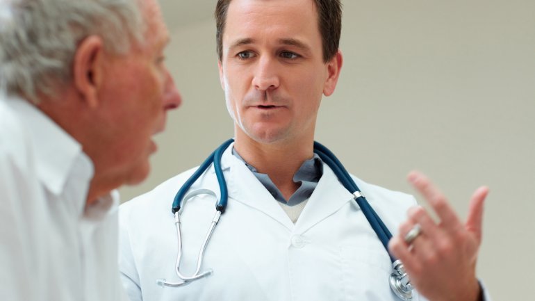 Das Bild zeigt ein Gespräch zwischen einem älteren Patienten und einem Arzt.