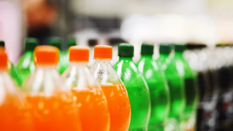 Zu sehen sind in Reihe angeordnete, verschiedenfarbige PET-Limonadenflaschen.