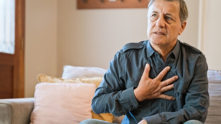 Mann mit Thymom fasst sich an schmerzendes Brustbein.