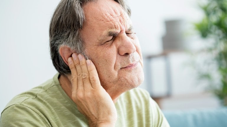 Mann mit Tinnitus fasst sich ans Ohr.