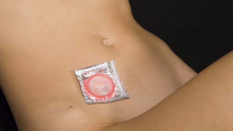 Das Bild zeigt den nackten Unterkörper einer Frau, auf der ein Kondom liegt.