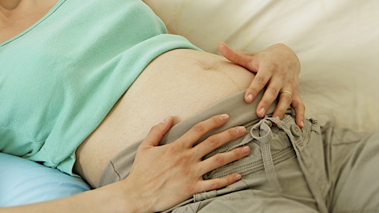 Schwangere hält sich den Bauch.