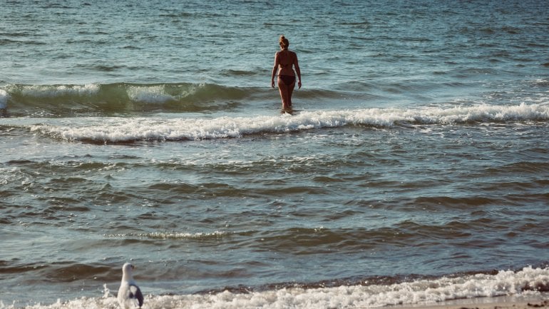Eine Frau watet ins Meer.