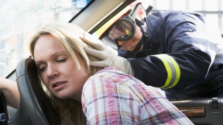 Ein Feuerwehrmann überprüft den Zustand einer bewusstlosen Frau im Auto.