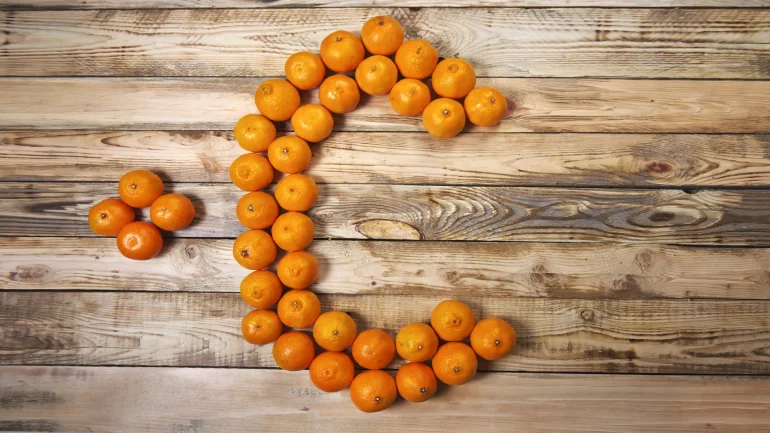 Das Bild zeigt mehrere Orangen auf einem Tisch, die ein C formen.
