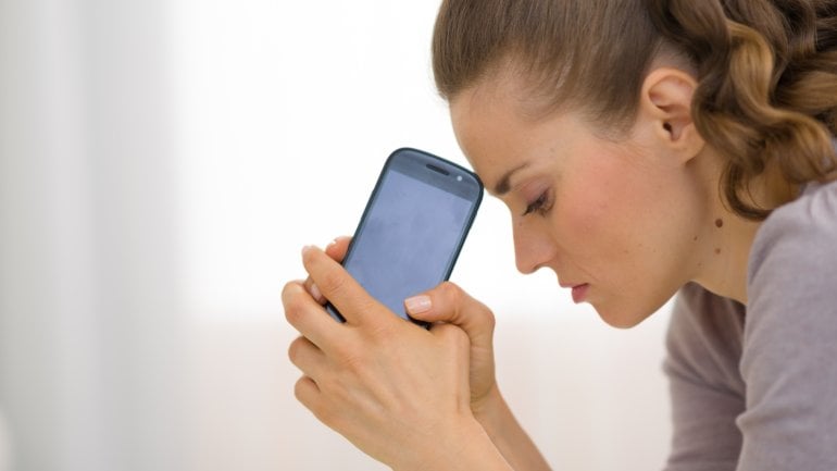 Eine Frau hält ratlos ihr Handy in den Händen.