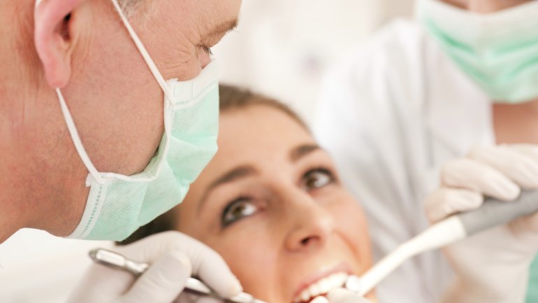 Das Bild zeigt einen Zahnarzt, der eine Frau untersucht.