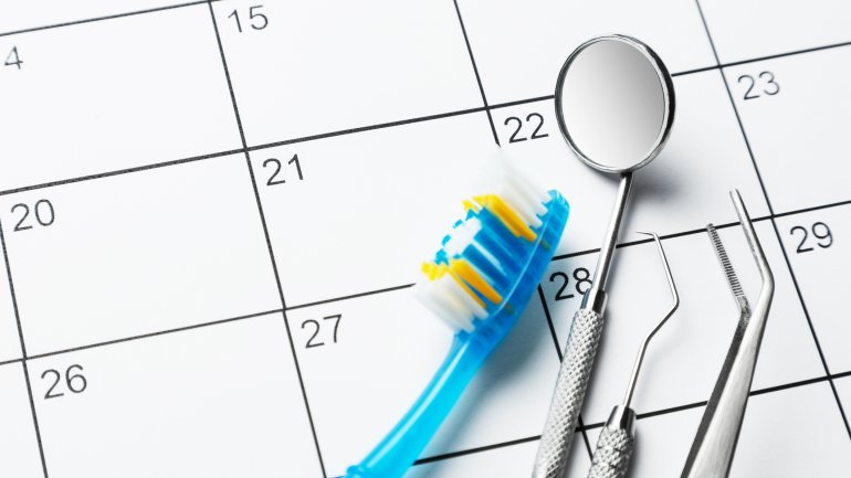 Man sieht eine Zahnbürste, einen Dentalsspiegel und andere Zahnarzt-Geräte auf einem Kalenderblatt.
