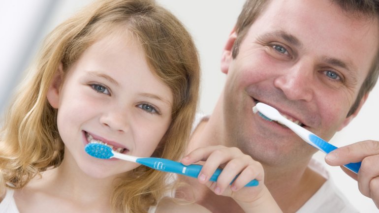 Das Bild zeigt ein Mädchen und einen Mann beim Zähneputzen.