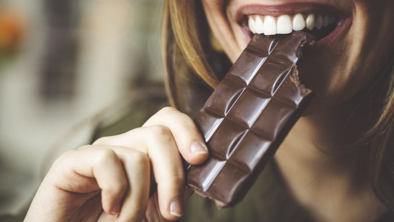 Eine Frau beißt in eine Tafel Schokolade.