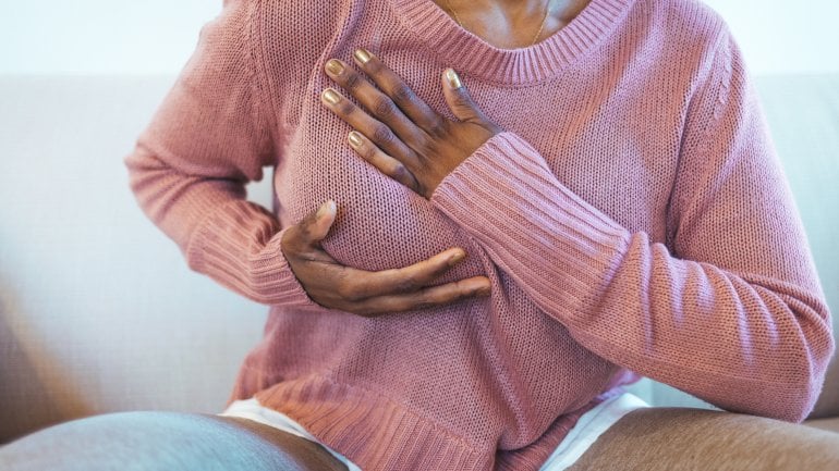 Brustkrebs: Frau tastet sich Brust mit den Händen ab.
